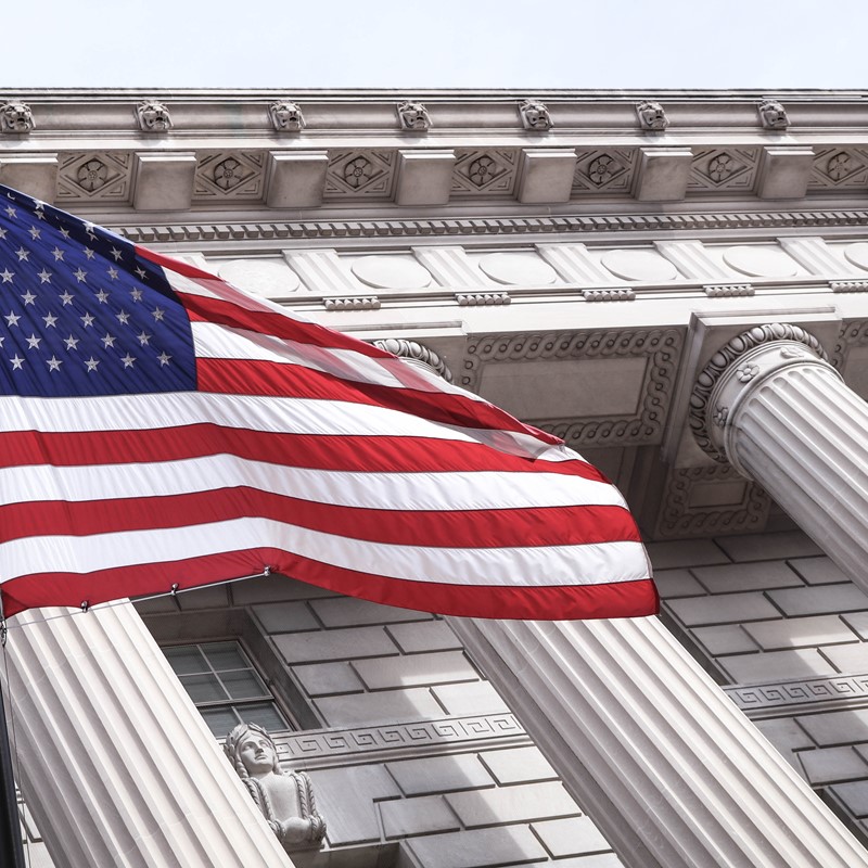 Picture of American Flag in front of building with greek columns.
