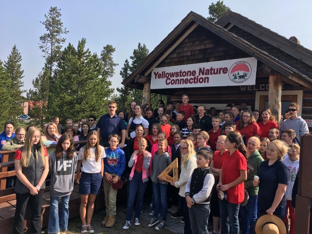 Photograph of students on an expeditionary field trip to Yellowstone. Students are gathered in front of a Park Ranger's cabin.